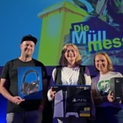 Die drei Finalist*innen des Poetry Slams "Die Müll Message" auf dem Heldenmarkt Berlin stehen auf der Bühne und halten ihre Preise in den Händen.